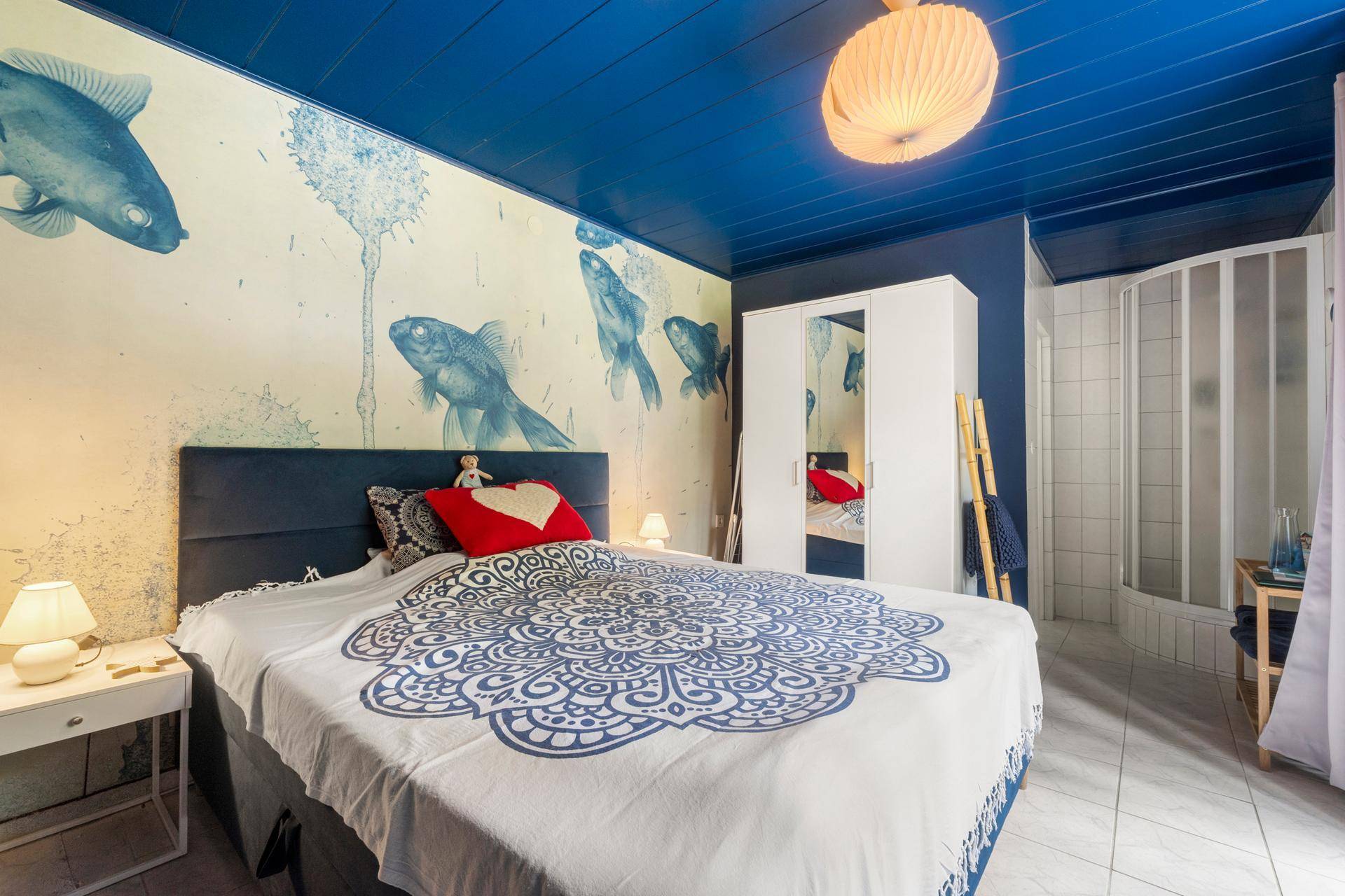 Schlafzimmer mit blauer Holzdecke, Fisch-Tapete und integrierter Duschkabine.