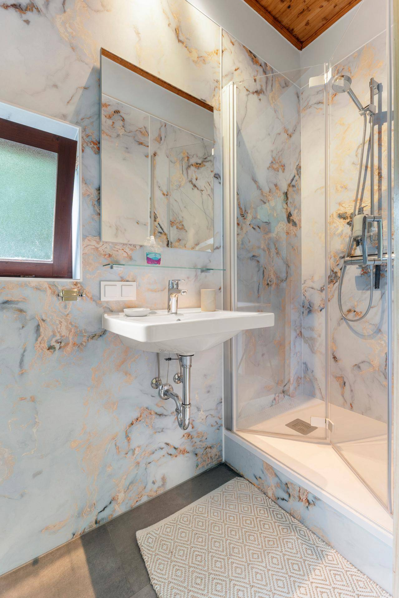 Stilvolles Badezimmer mit Dusche, WC und Waschbecken, umgeben von luxuriösen Marmorfliesen.