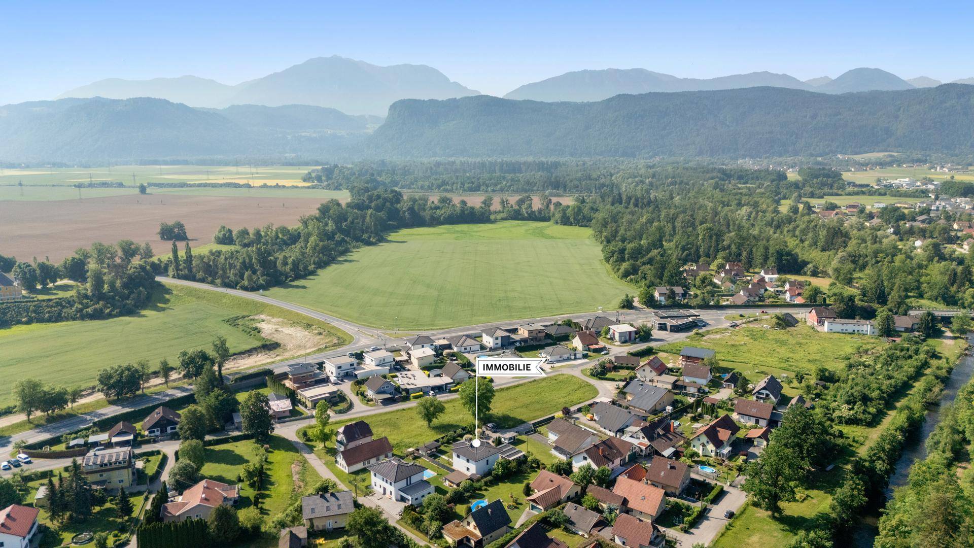 Luftaufnahme der Immobilie in ländlicher Umgebung mit Bergen im Hintergrund.