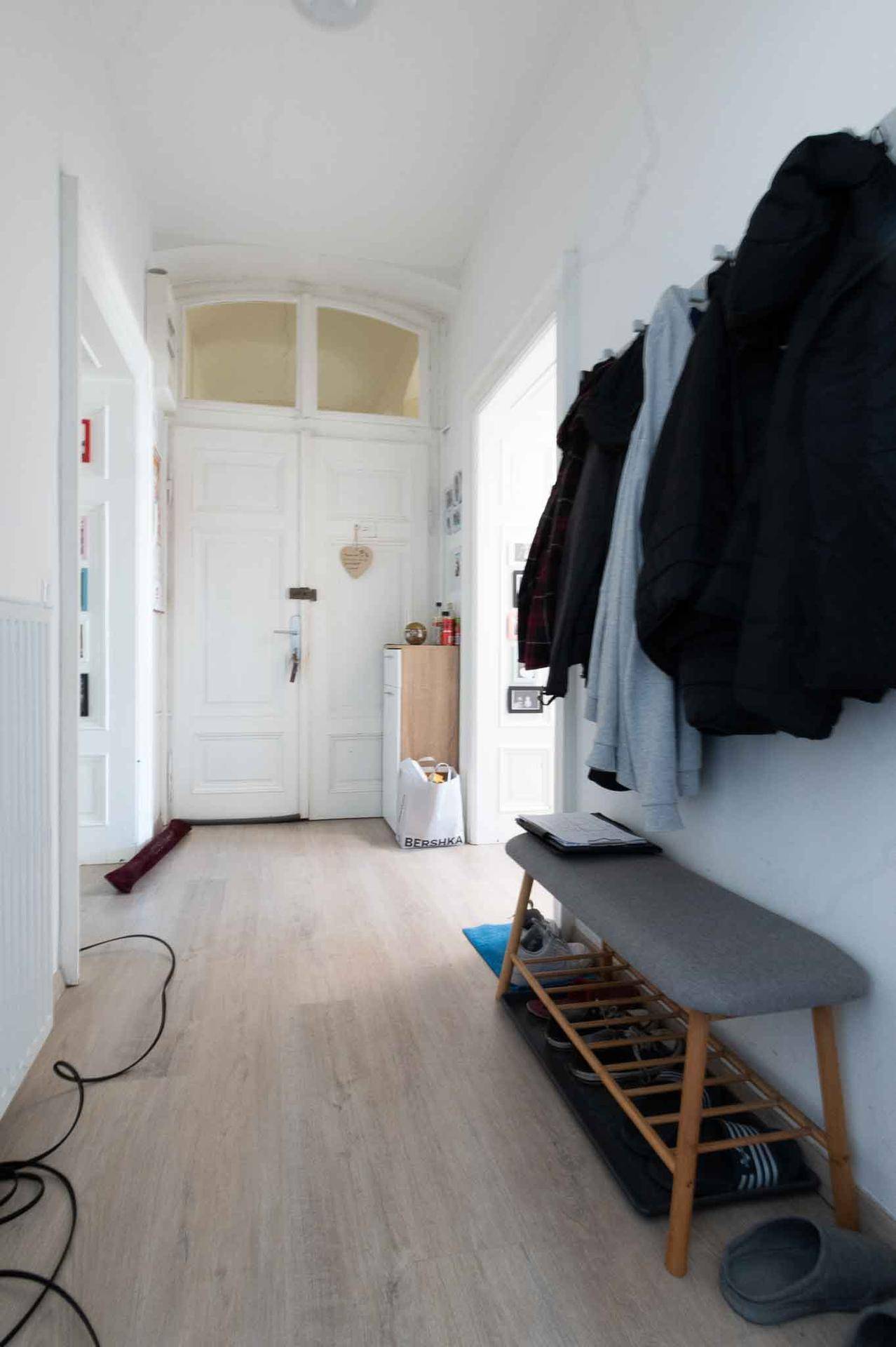 Eingangsbereich mit hellem Laminatboden, Garderobe und einer Bank, die zum Verweilen einlädt.