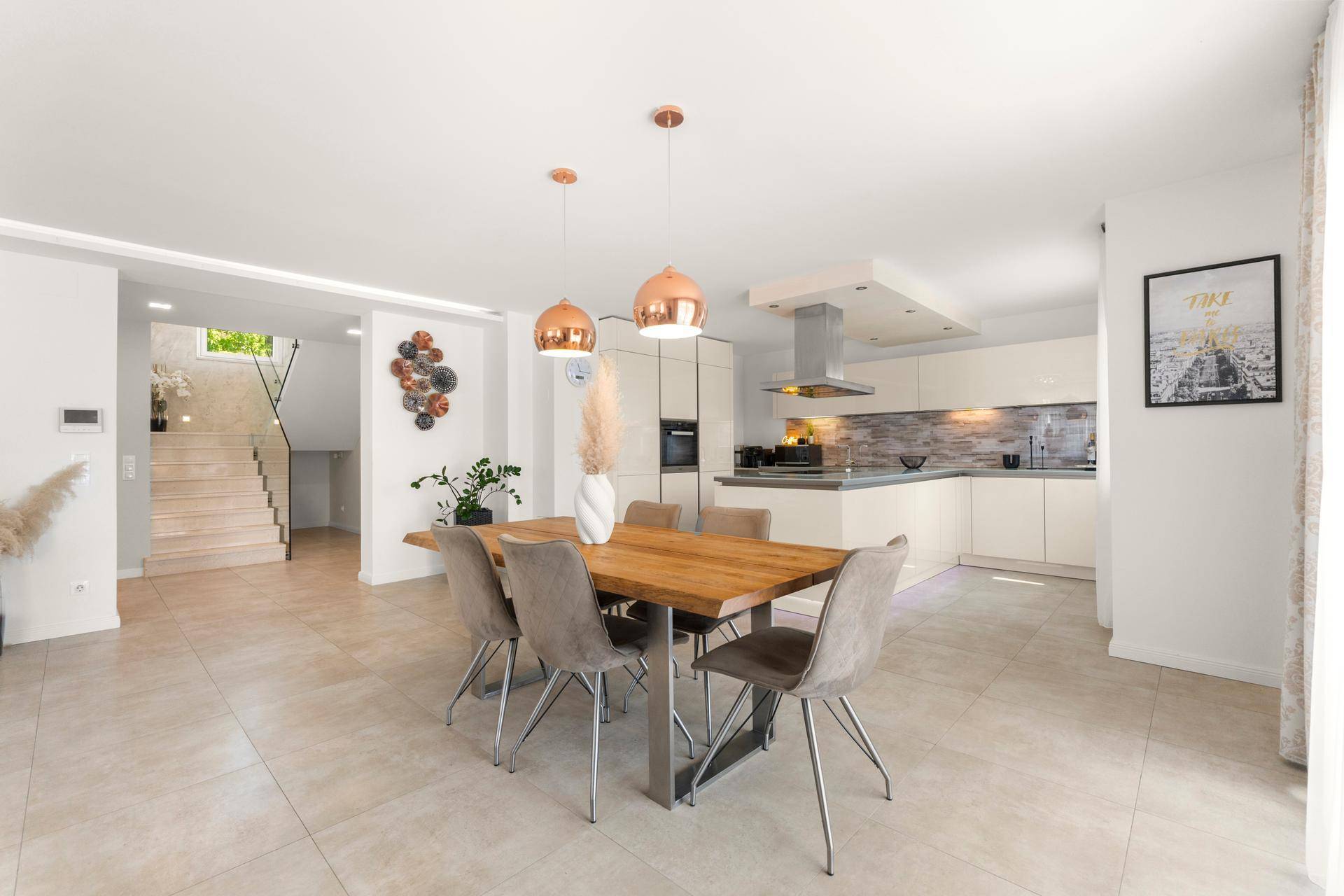 Eleganter Essbereich mit Holztisch und modernen Pendelleuchten, angrenzend an die Küche.