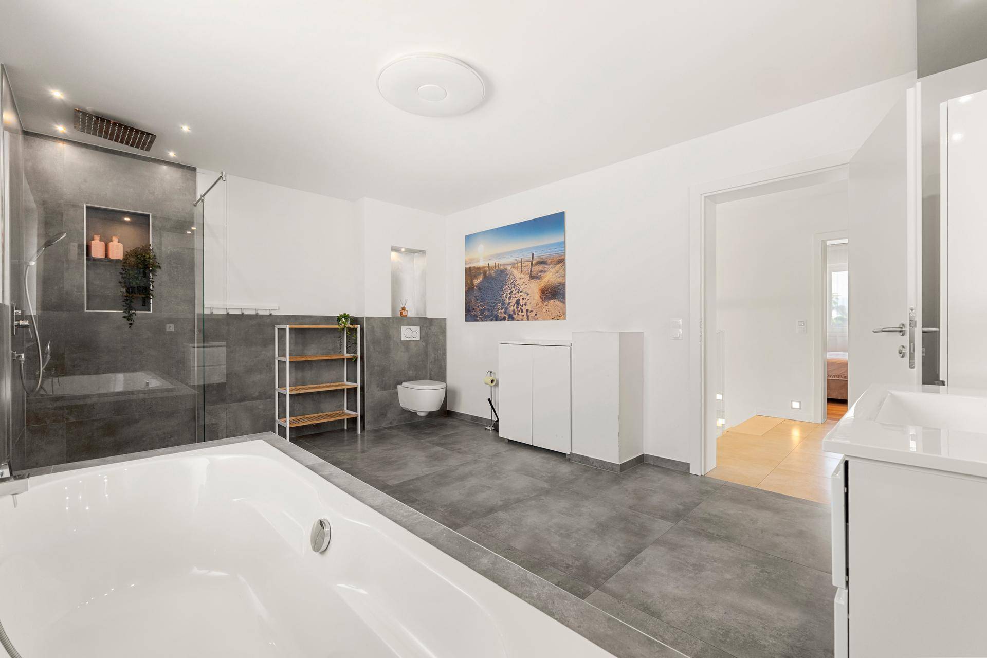 Geräumiges Badezimmer mit Badewanne, Dusche und modernem Design, verbunden mit dem Schlafbereich.