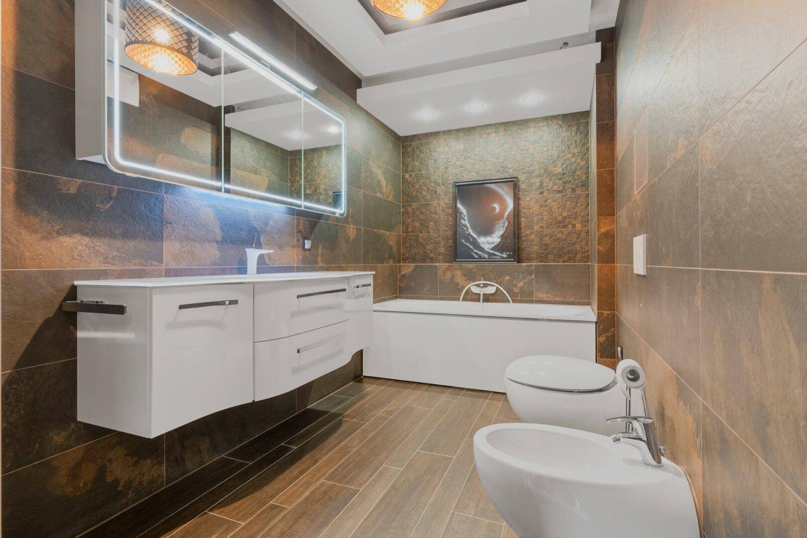 Modernes Badezimmer mit Badewanne, Bidet, schwebendem Waschtisch und großformatigen Fliesen.