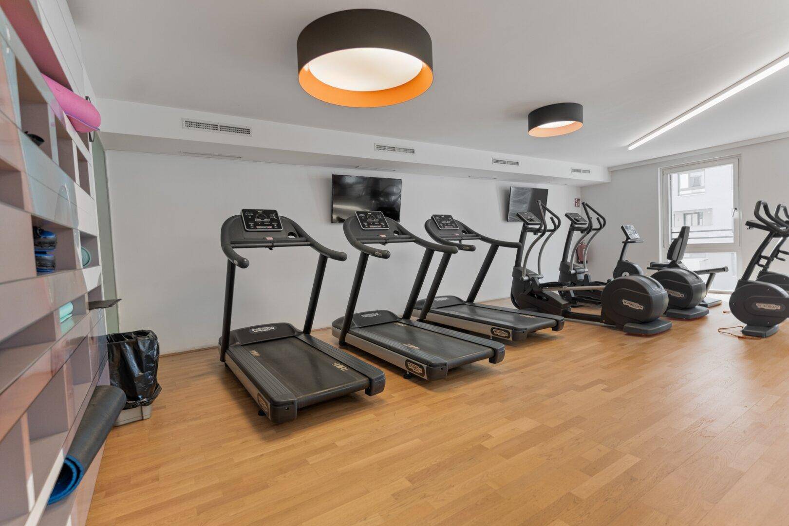 Gut ausgestatteter Fitnessraum mit Laufbändern und verschiedenen Trainingsgeräten für Bewohner.