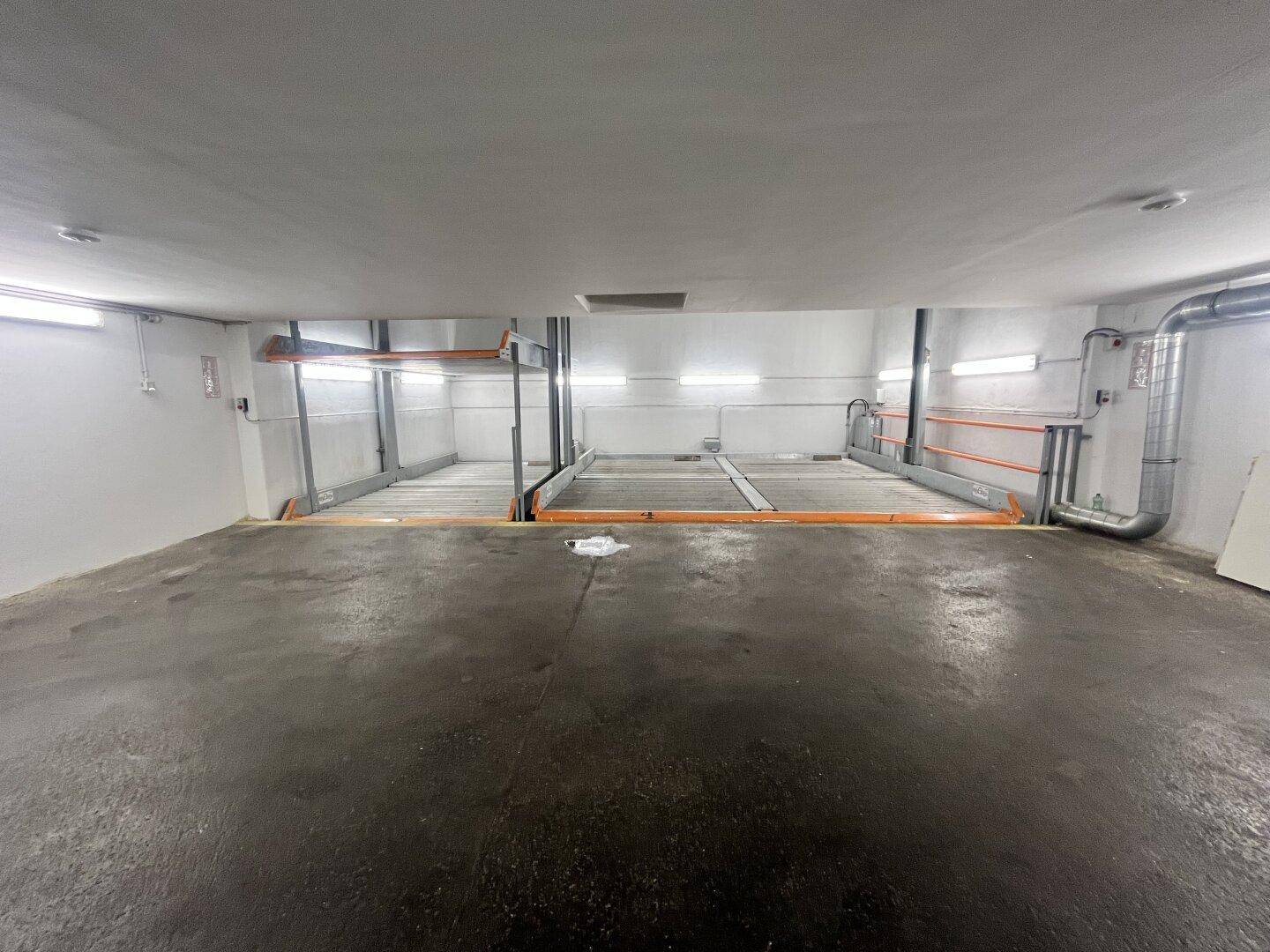 Geräumige Tiefgarage mit zwei Stapelparksystemen und viel freiem Platz auf dem Betonboden.