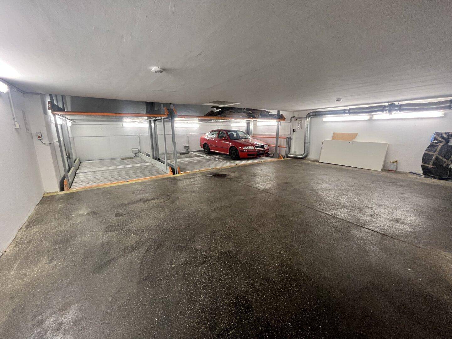 Tiefgarage mit modernem Stapelparksystem und einem geparkten Fahrzeug, beleuchtet von Deckenleuchten.