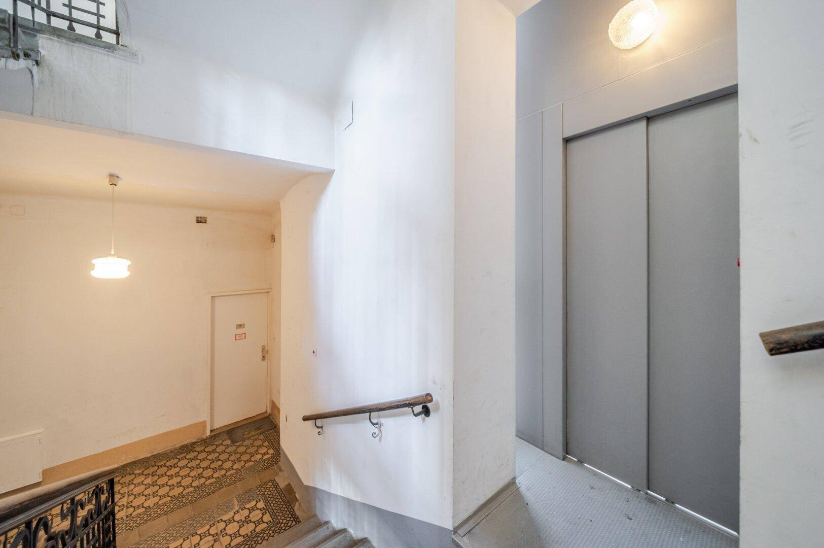 Treppenhaus mit Aufzug und Handlauf, typisch für ein Mehrfamilienhaus.