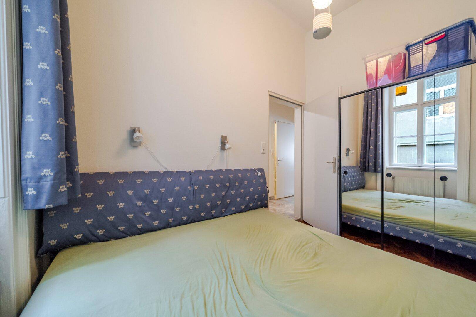 Schlafzimmer mit großem Spiegelkleiderschrank und Zugang zu einem weiteren Raum.