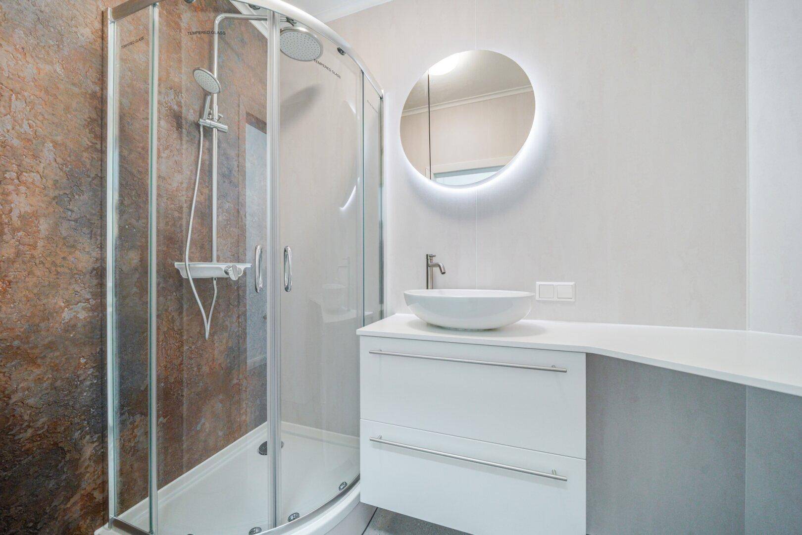 Modernes Badezimmer mit Eckdusche, beleuchtetem Spiegel und stilvollem Aufsatzwaschbecken.