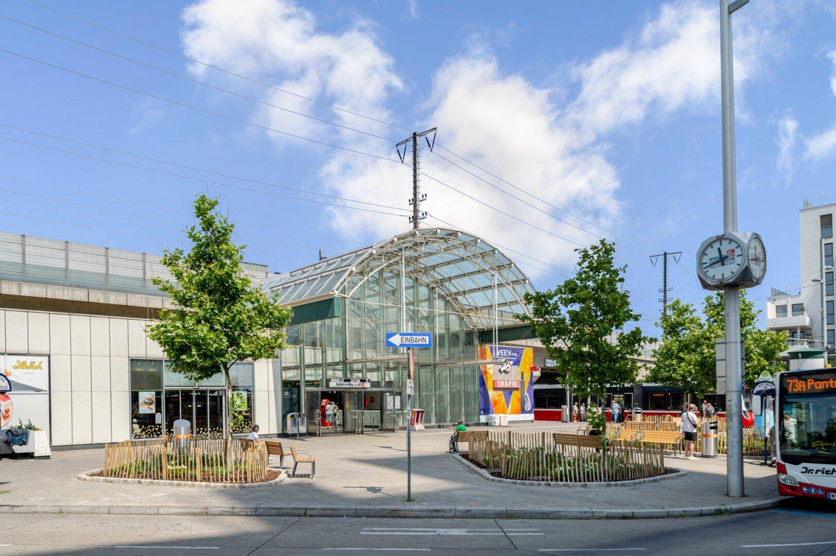 Moderne Architektur eines Bahnhofs oder Verkehrsknotenpunkts mit Glasfassade und Bushaltestelle.