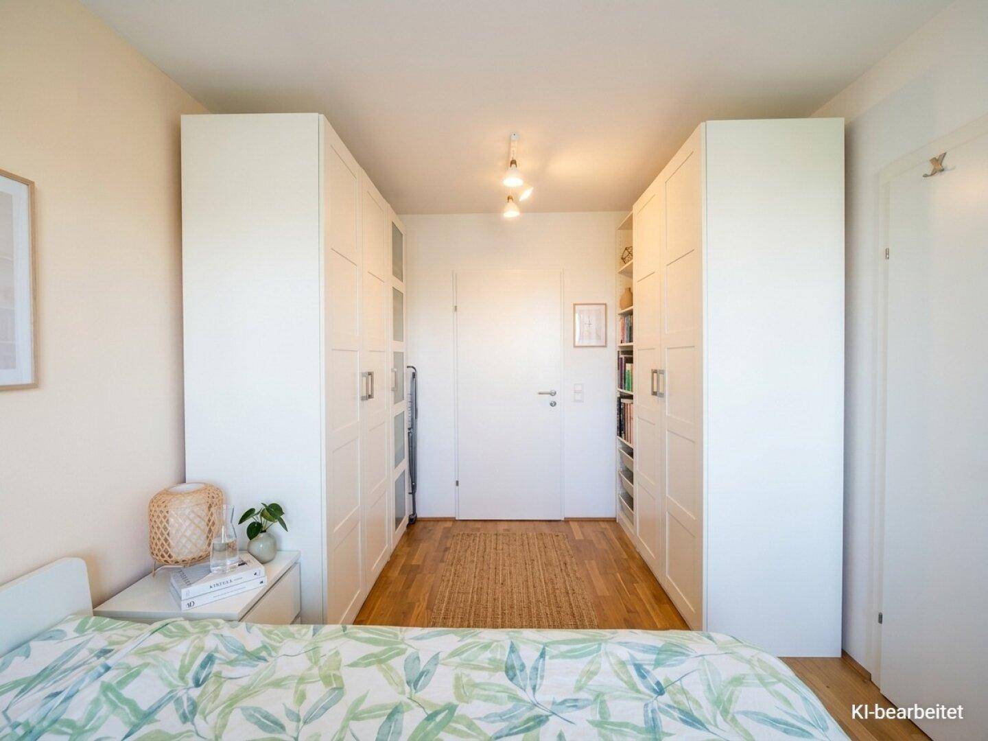 Schlafzimmer mit großen weißen Kleiderschränken und hellem Holzboden.