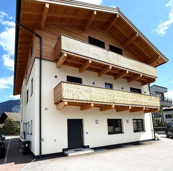 Seitenansicht des modernen Gebäudes mit mehreren Holzbalkonen und einer klaren architektonischen Linie.