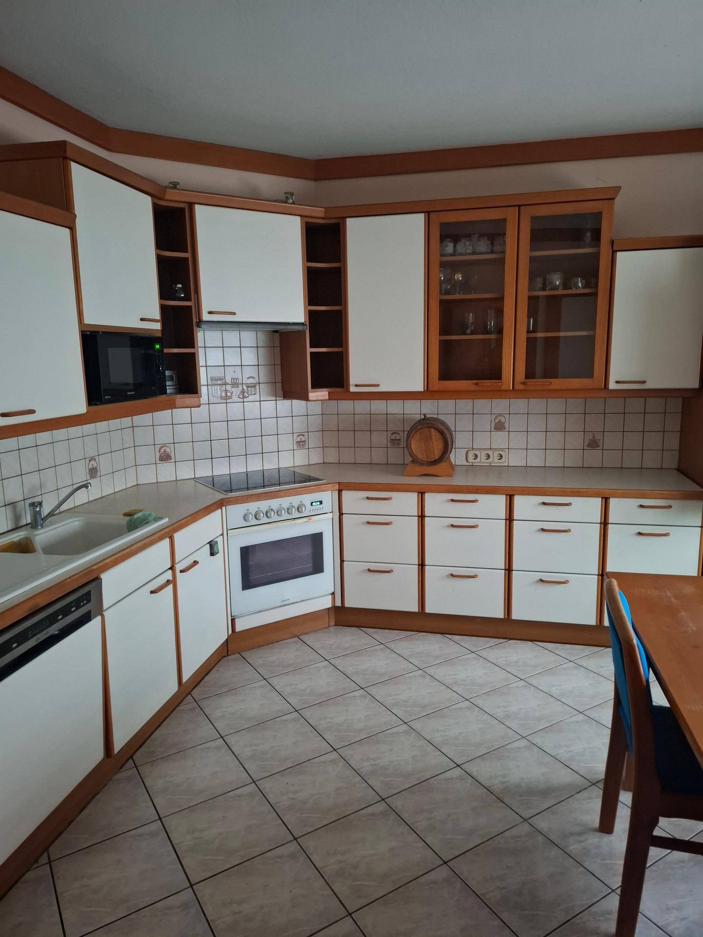 Traditionelle Küche mit weißen Holzschränken, Fliesenboden und Essbereich.