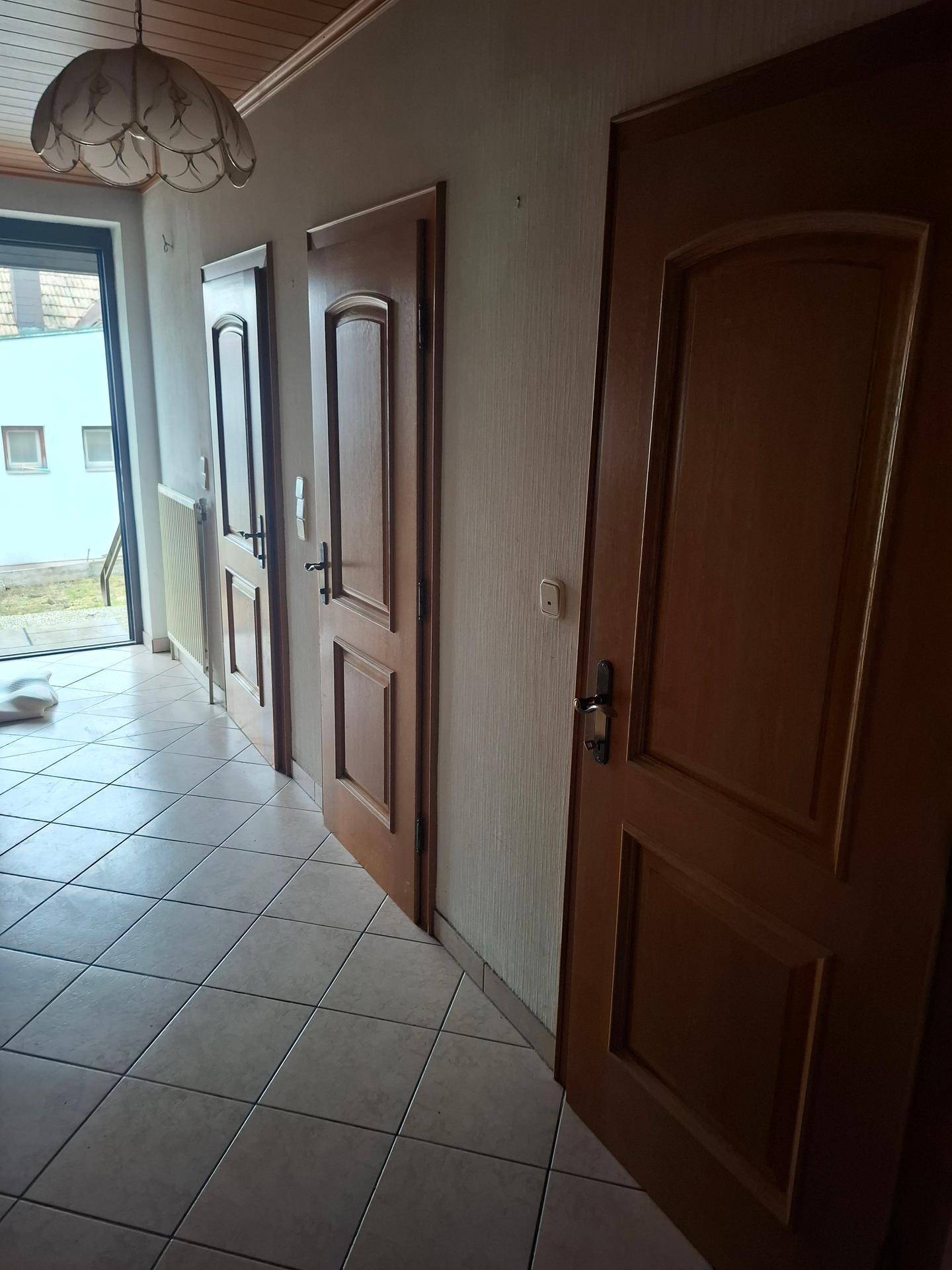 Heller Flur mit Fliesenboden und mehreren Holztüren, die zu den Zimmern führen.