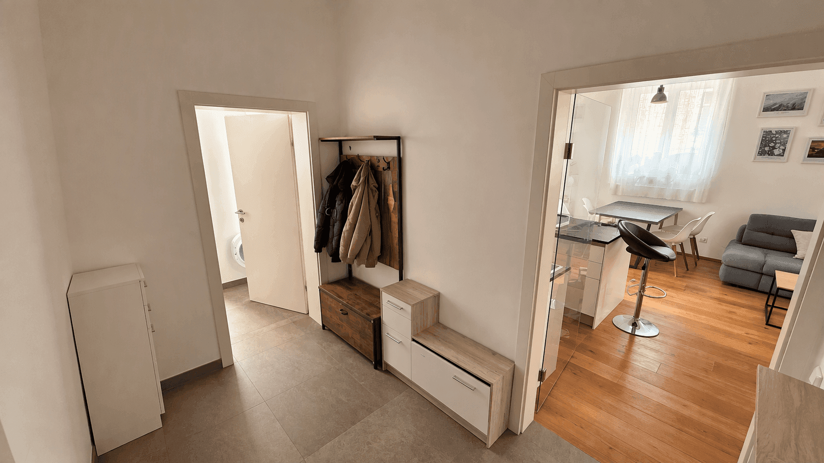 Heller Eingangsbereich mit Garderobe, Schuhschränken und Fliesenboden.