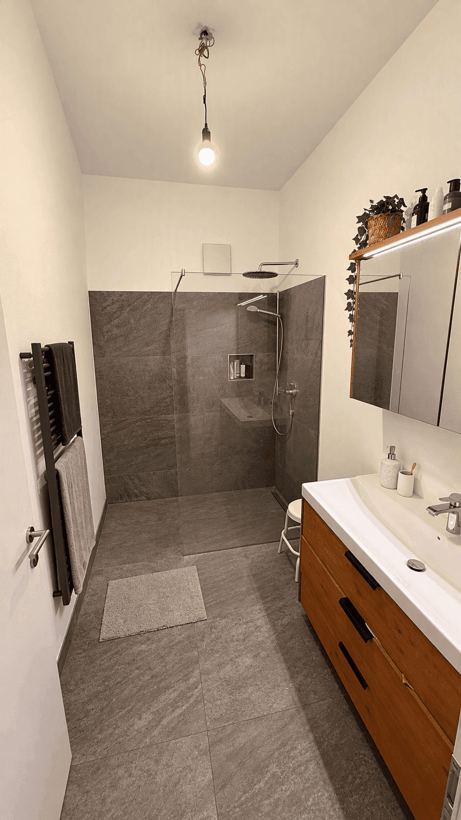 Modernes Badezimmer mit ebenerdiger Dusche, Waschtisch und beheiztem Handtuchhalter.
