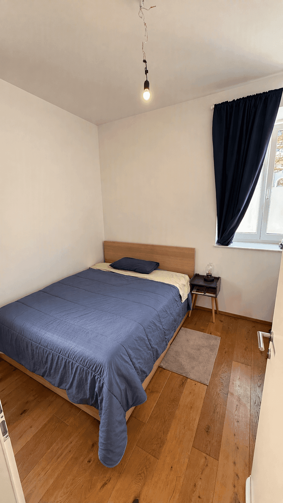 Gemütliches Schlafzimmer mit Doppelbett, Holzboden und Fenster.