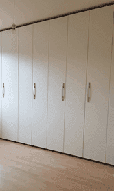 Helles Schlafzimmer mit integrierten weißen Einbauschränken und einem gepflegten Holzfußboden.