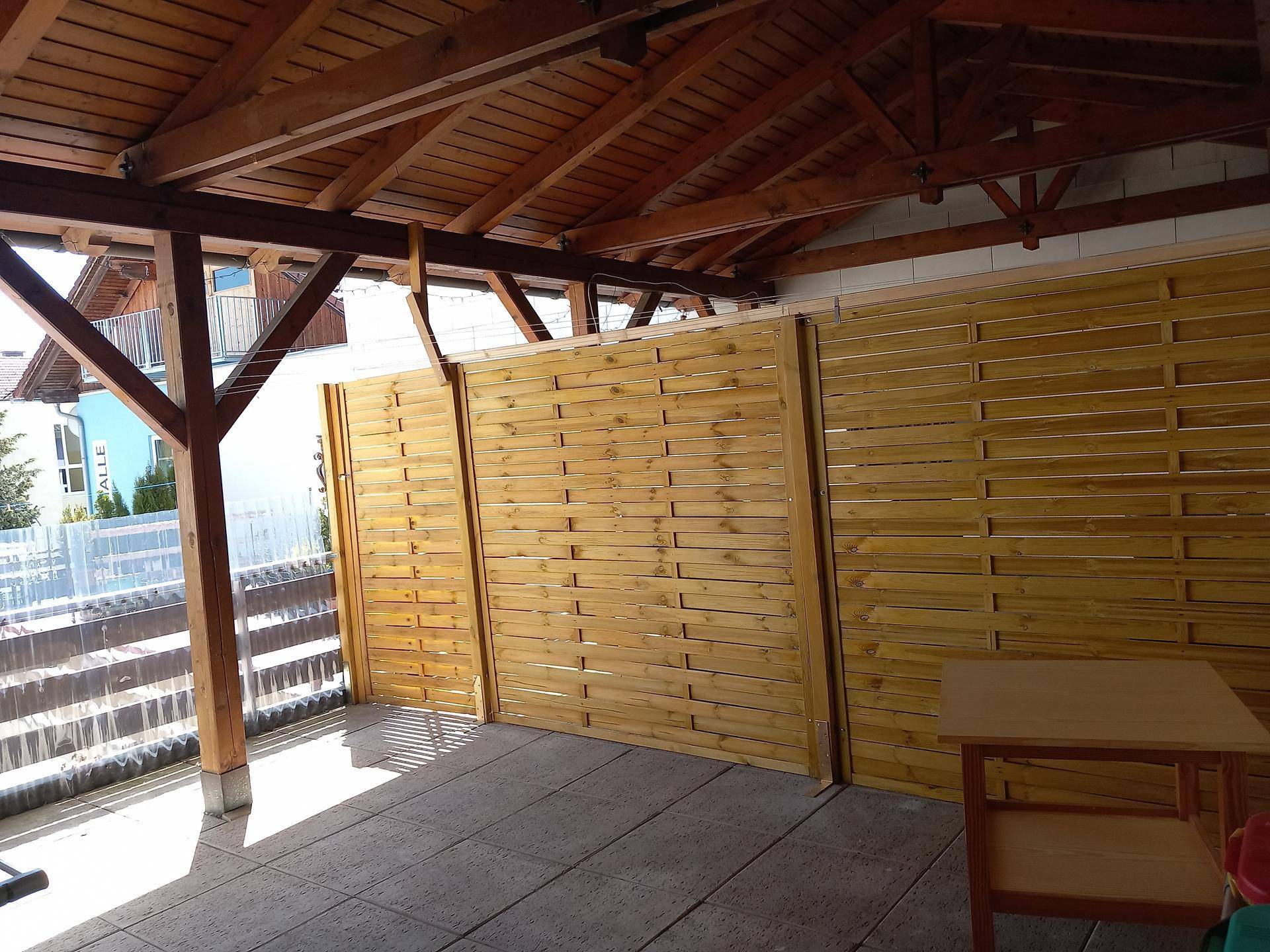 Geräumige überdachte Terrasse mit Holzdach und Sichtschutz, ideal für entspannte Stunden im Freien.