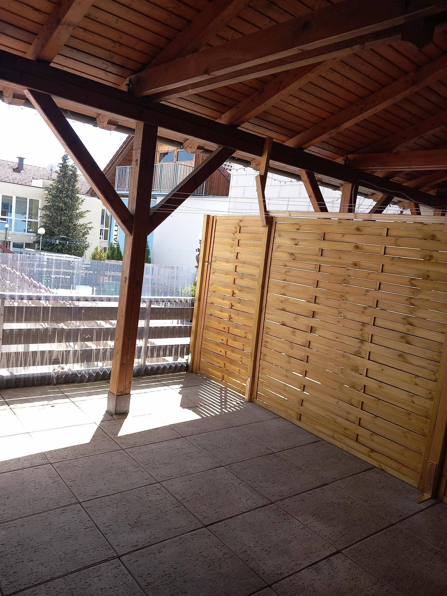 Überdachter Außenbereich mit Holzbalken und Sichtschutz, bietet einen Blick auf die Umgebung.