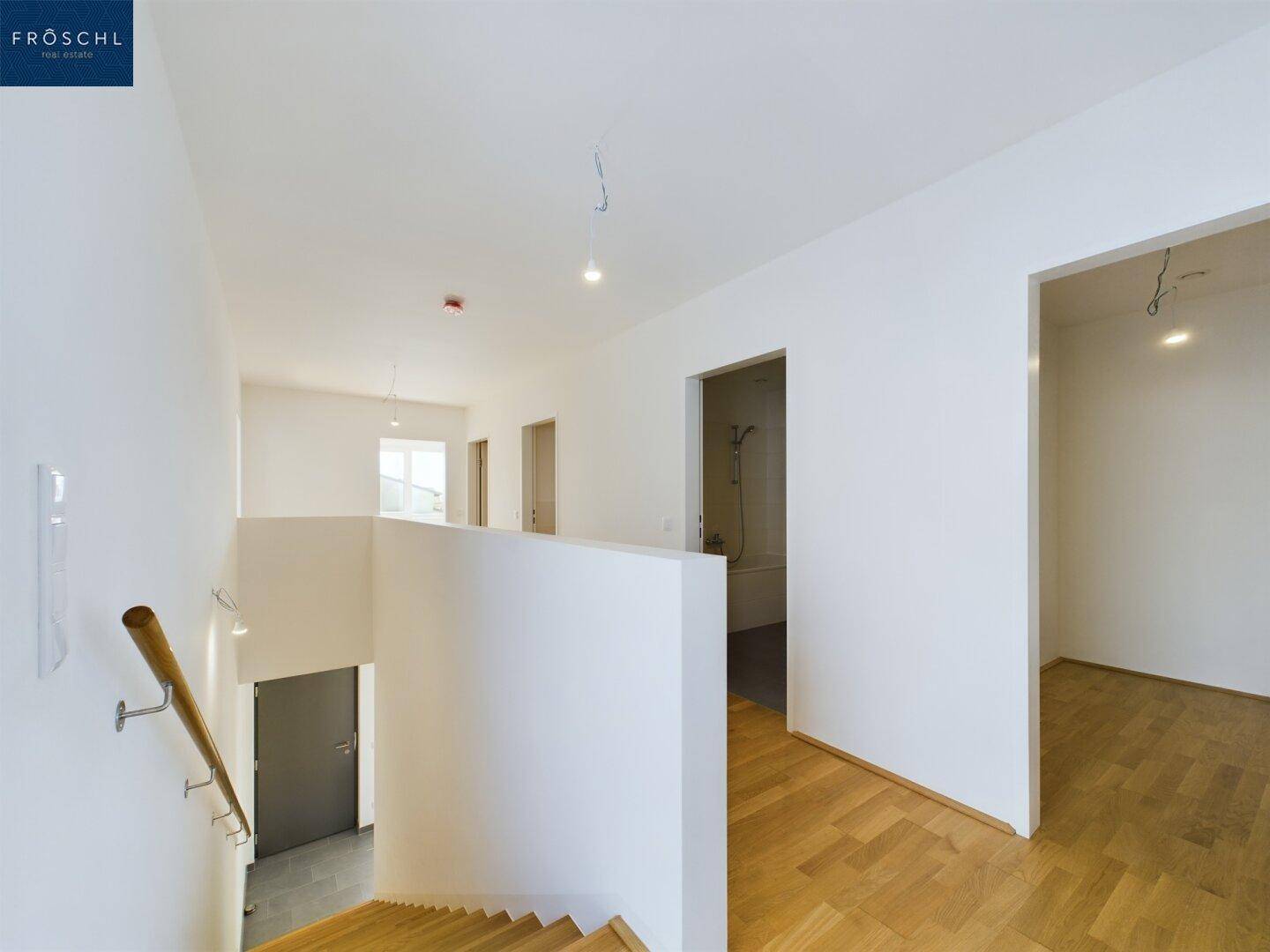 Heller Flur mit Holztreppe und Zugang zu den oberen Zimmern, modern und funktional gestaltet.