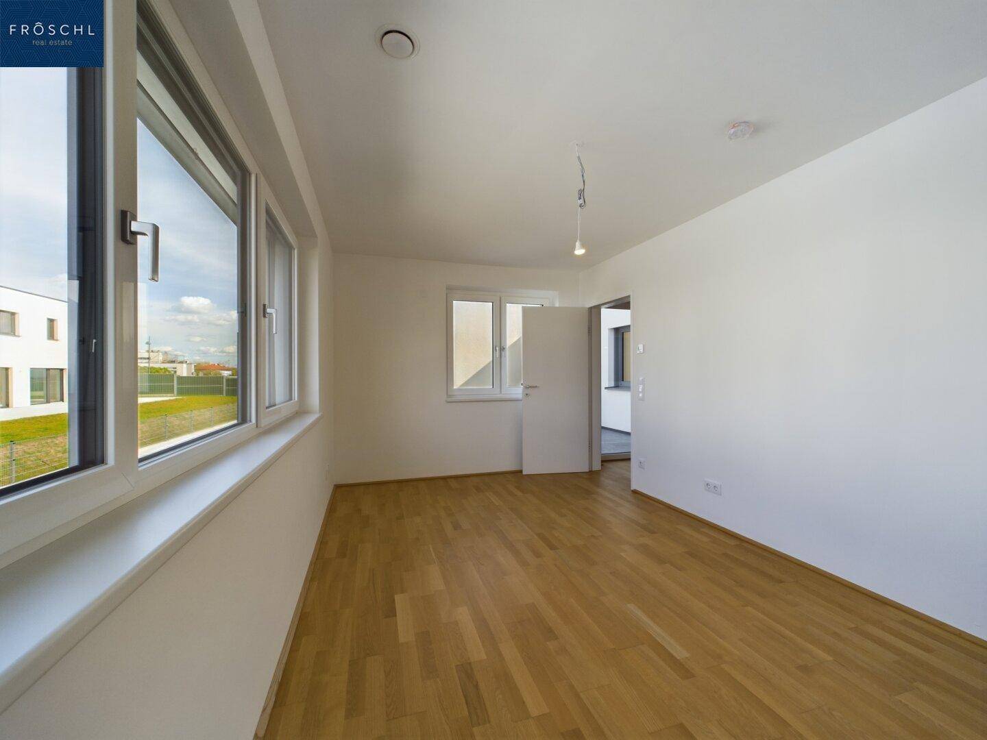 Geräumiges Schlafzimmer mit Parkettboden und großen Fenstern, die viel Licht spenden.