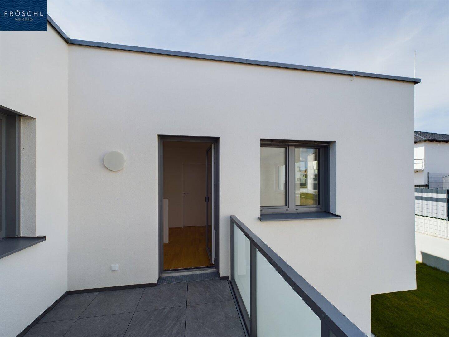 Kleiner Balkon mit Fliesenboden und moderner Glasbrüstung, zugänglich vom Schlafzimmer.