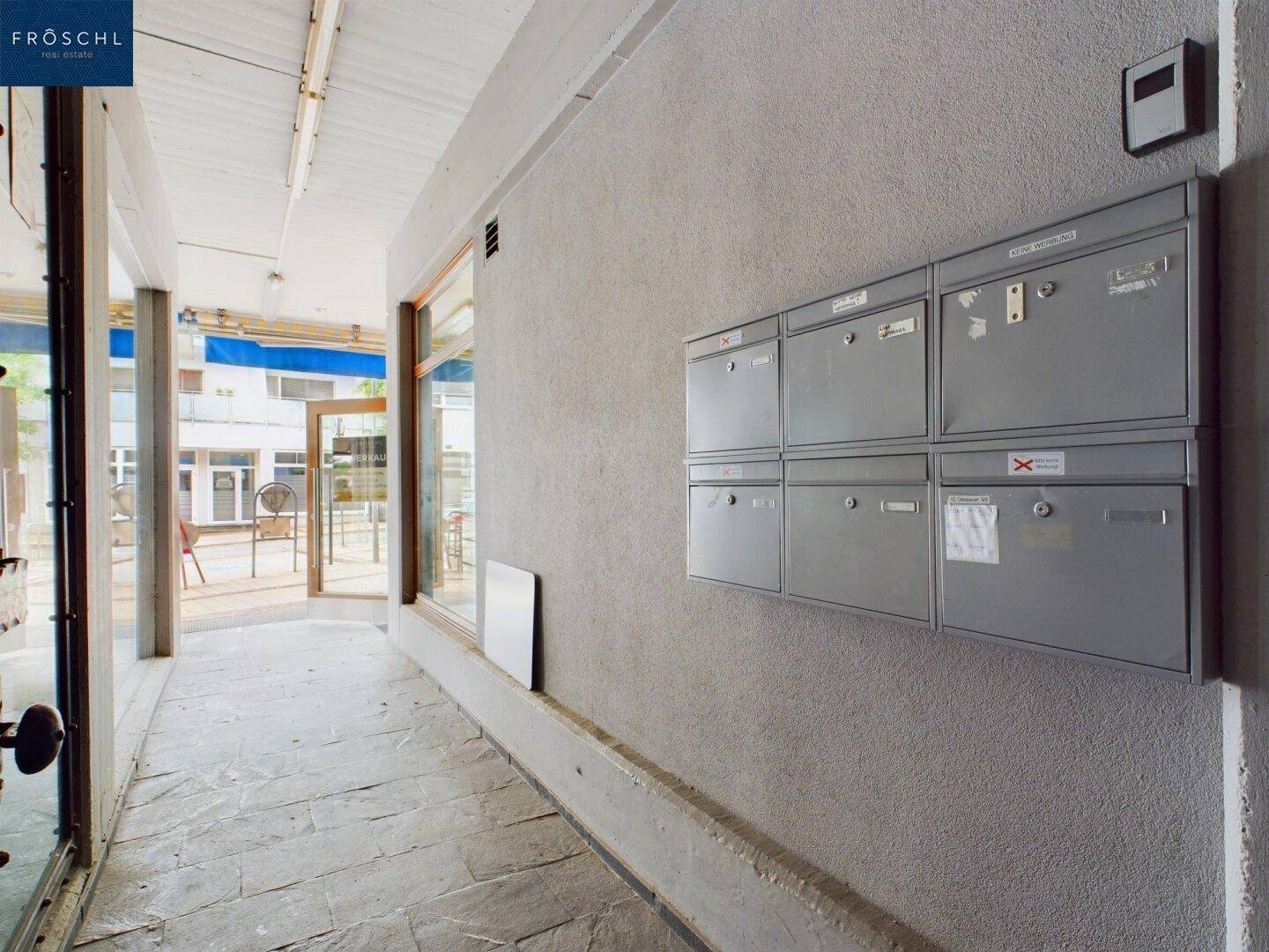 Eingangsbereich eines Gebäudes mit Briefkästen an der Wand und Blick auf den Außenbereich.