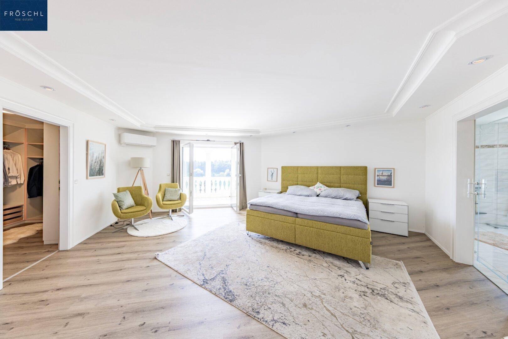 Helles Schlafzimmer mit Doppelbett, Zugang zum begehbaren Kleiderschrank und Balkon.