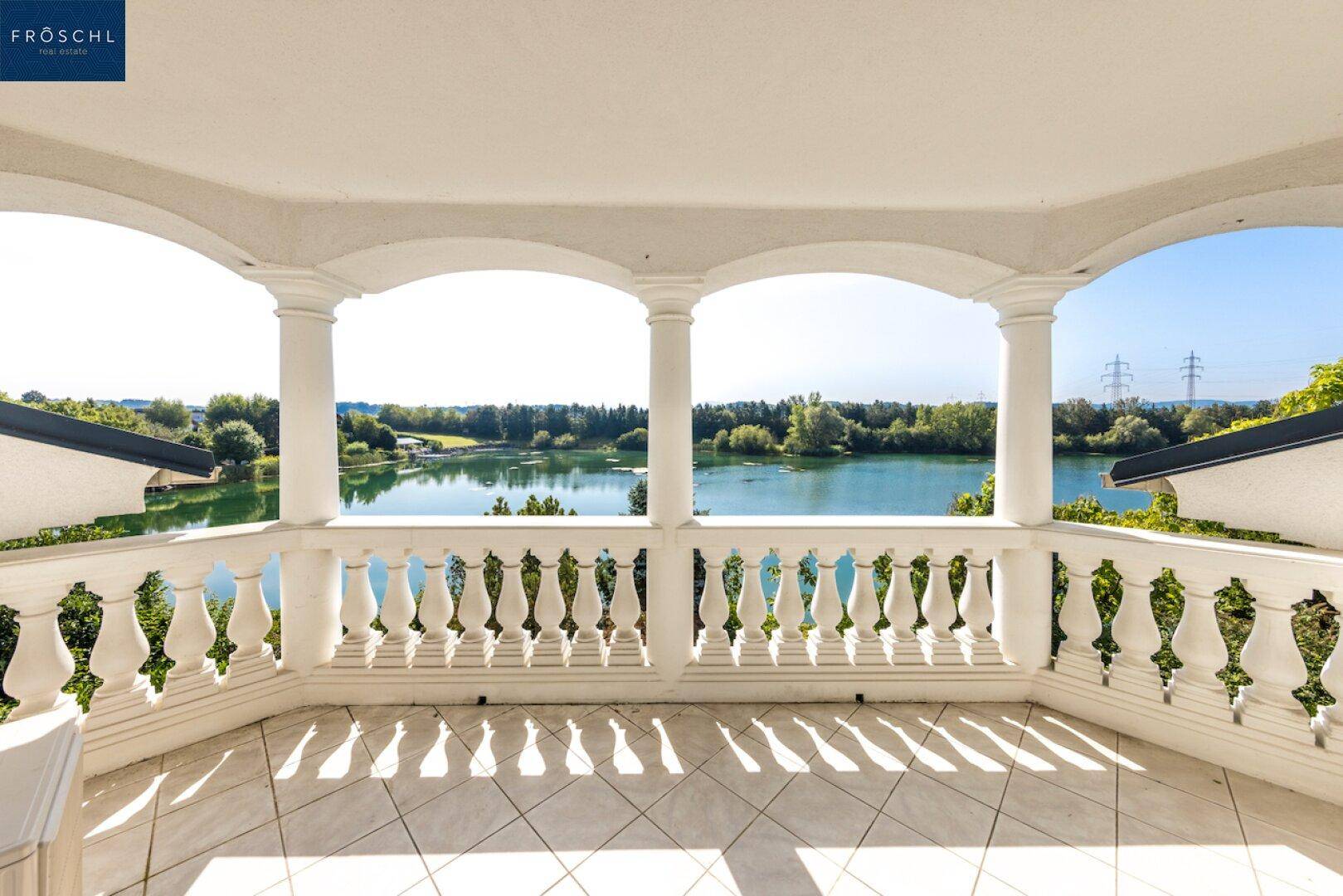 Geräumiger Balkon mit klassischer Balustrade und weitem Blick über den See.