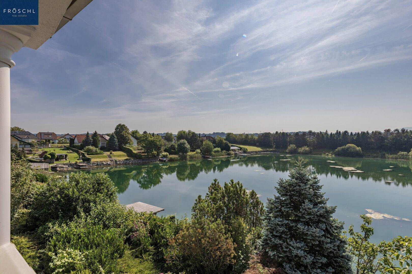 Panoramablick vom Balkon auf den ruhigen See und die grüne Landschaft.