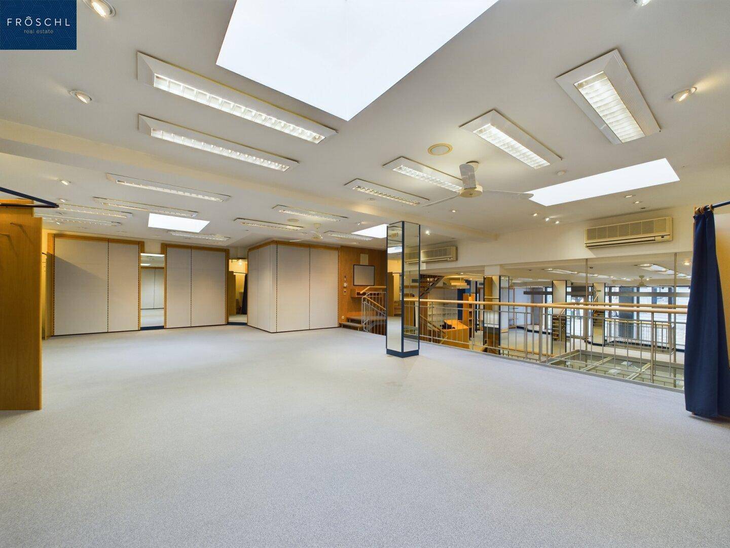 Heller Verkaufsraum im Obergeschoss mit Teppichboden, Deckenventilatoren und Klimaanlagen für angenehmes Klima.