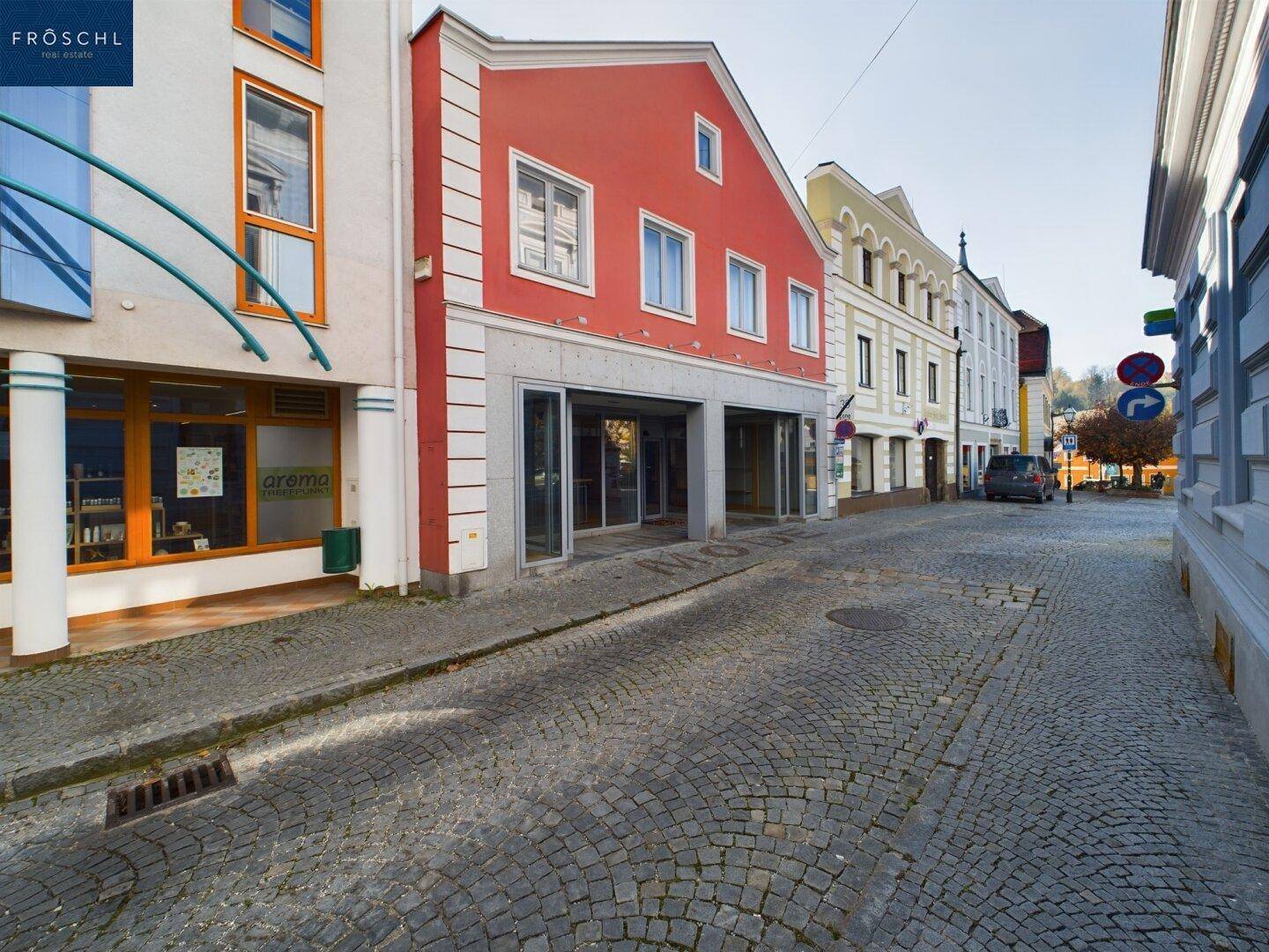 Weitläufiger Blick auf die gepflasterte Straße mit dem roten Gebäude und der angrenzenden Architektur.