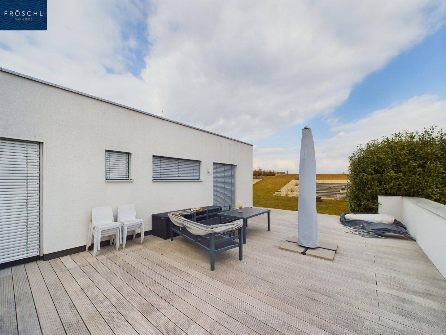 Große Holzterrasse mit Gartenmöbeln und Blick auf den weitläufigen Gartenbereich.