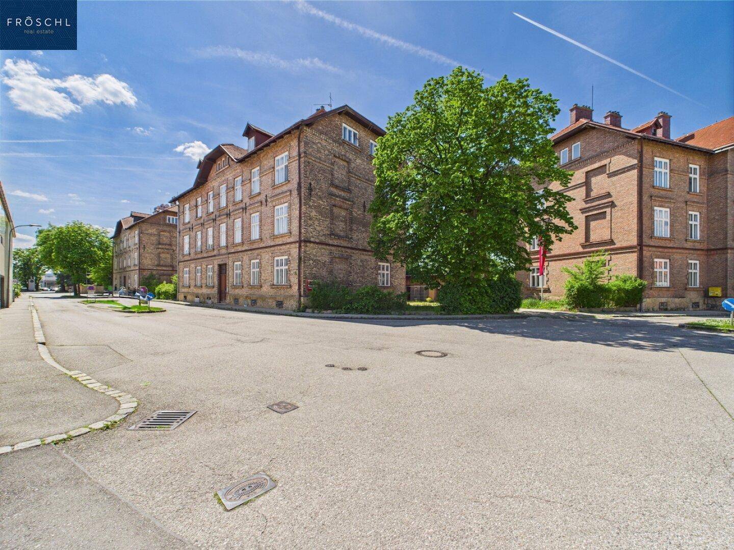 Breite Straße umgeben von mehreren großen, traditionellen Backsteingebäuden unter blauem Himmel.