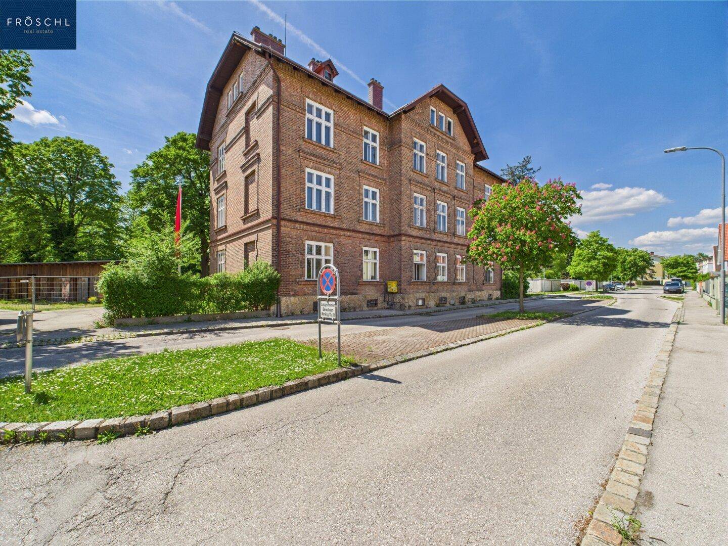 Historisches Ziegelgebäude mit traditioneller Architektur und einem Baum an der Straßenseite.