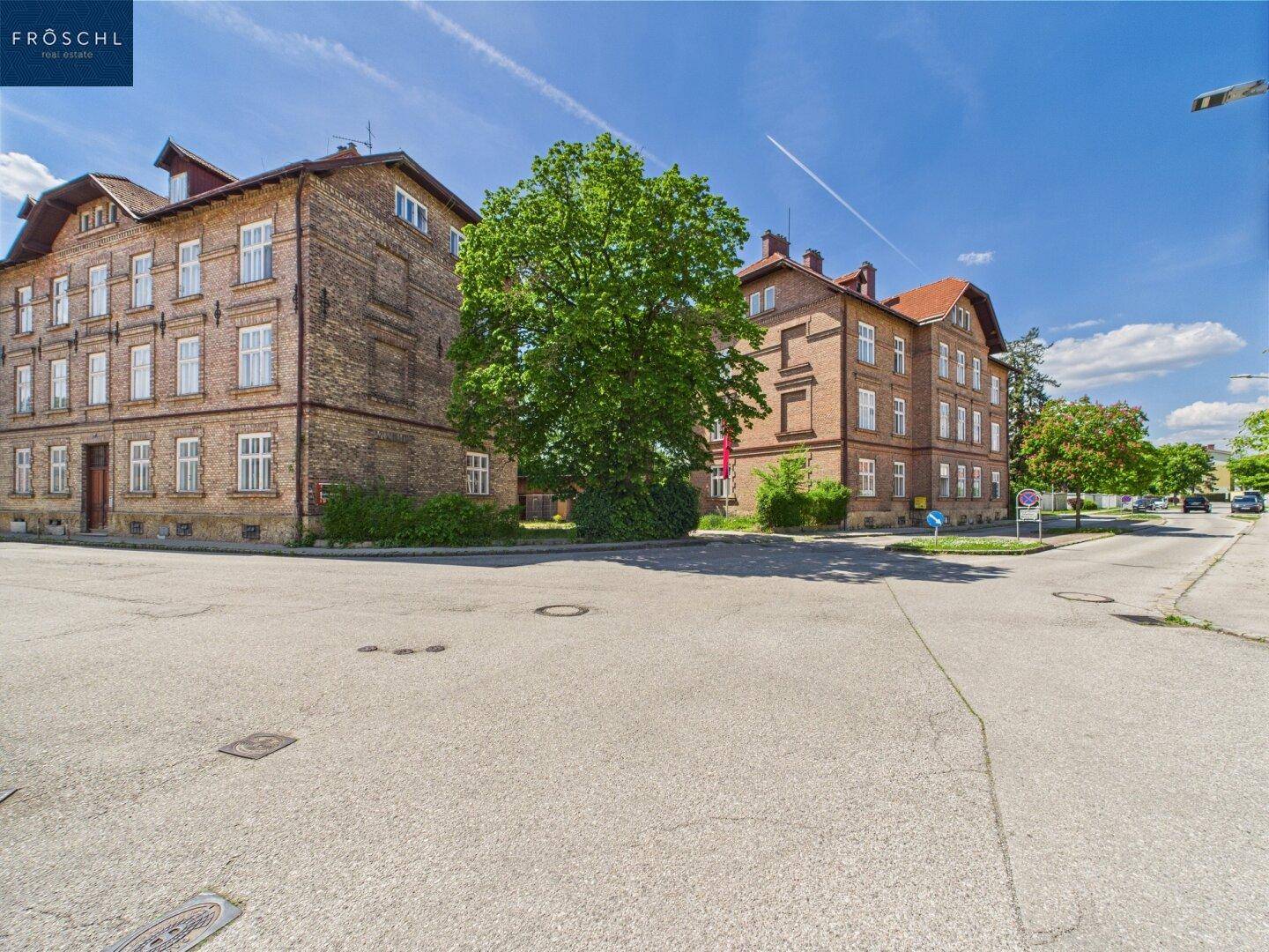 Kreuzung mit mehreren historischen Backsteingebäuden und viel Grün in der Umgebung.