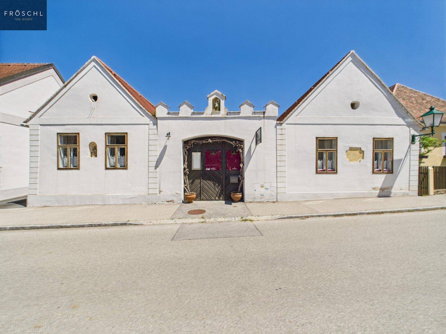 Symmetrische Fassade eines historischen Gebäudes mit zentralem Torbogen und traditionellen Fenstern.