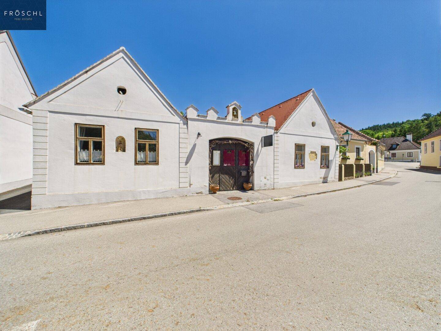 Charmantes historisches Gebäude mit weißer Fassade und traditionellen Fenstern an einer Dorfstraße.