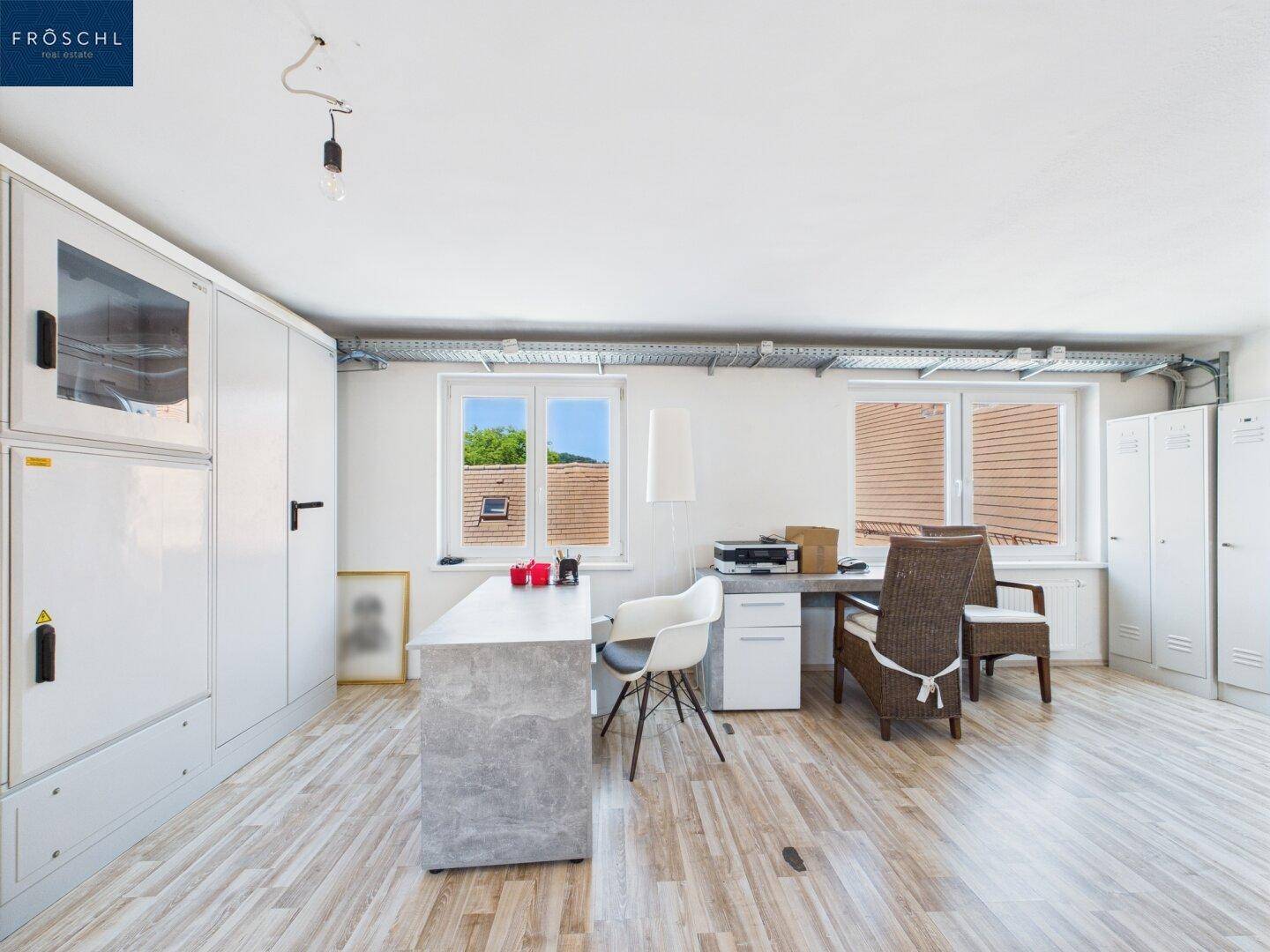 Helles Büro mit Laminatboden, großen Fenstern und viel Stauraum.