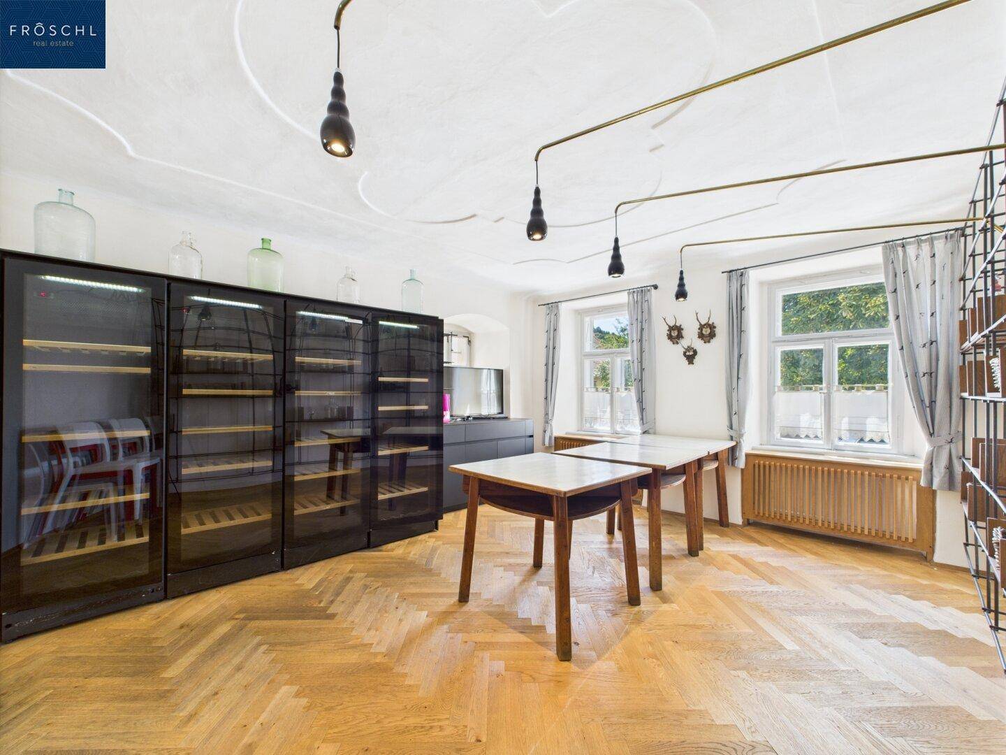 Eleganter Raum mit Fischgrätparkett, Weinschränken und dekorativer Stuckdecke.