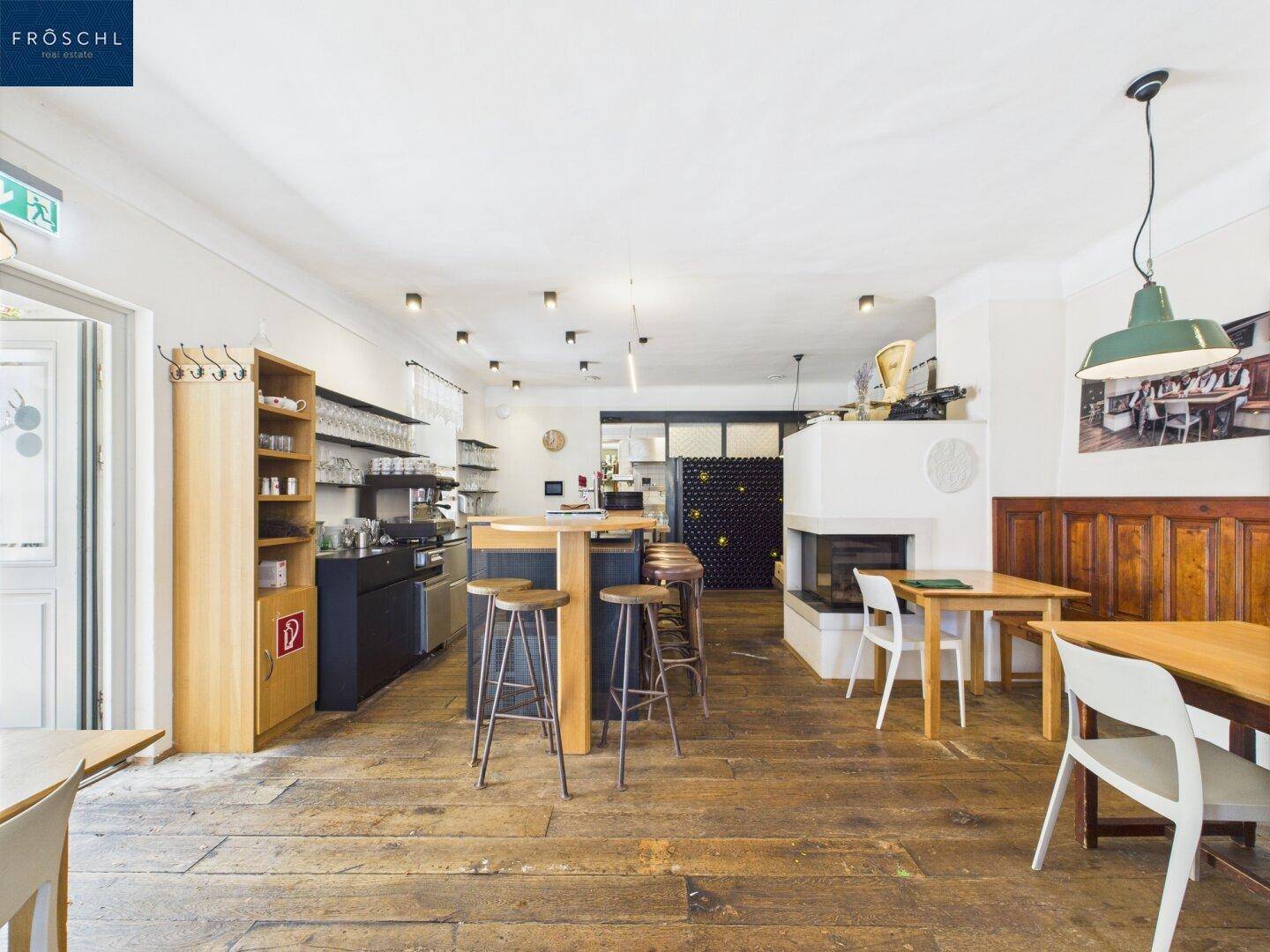 Geräumiger Gastraum mit Holzboden, moderner Bar und Kamin, ideal für Veranstaltungen.