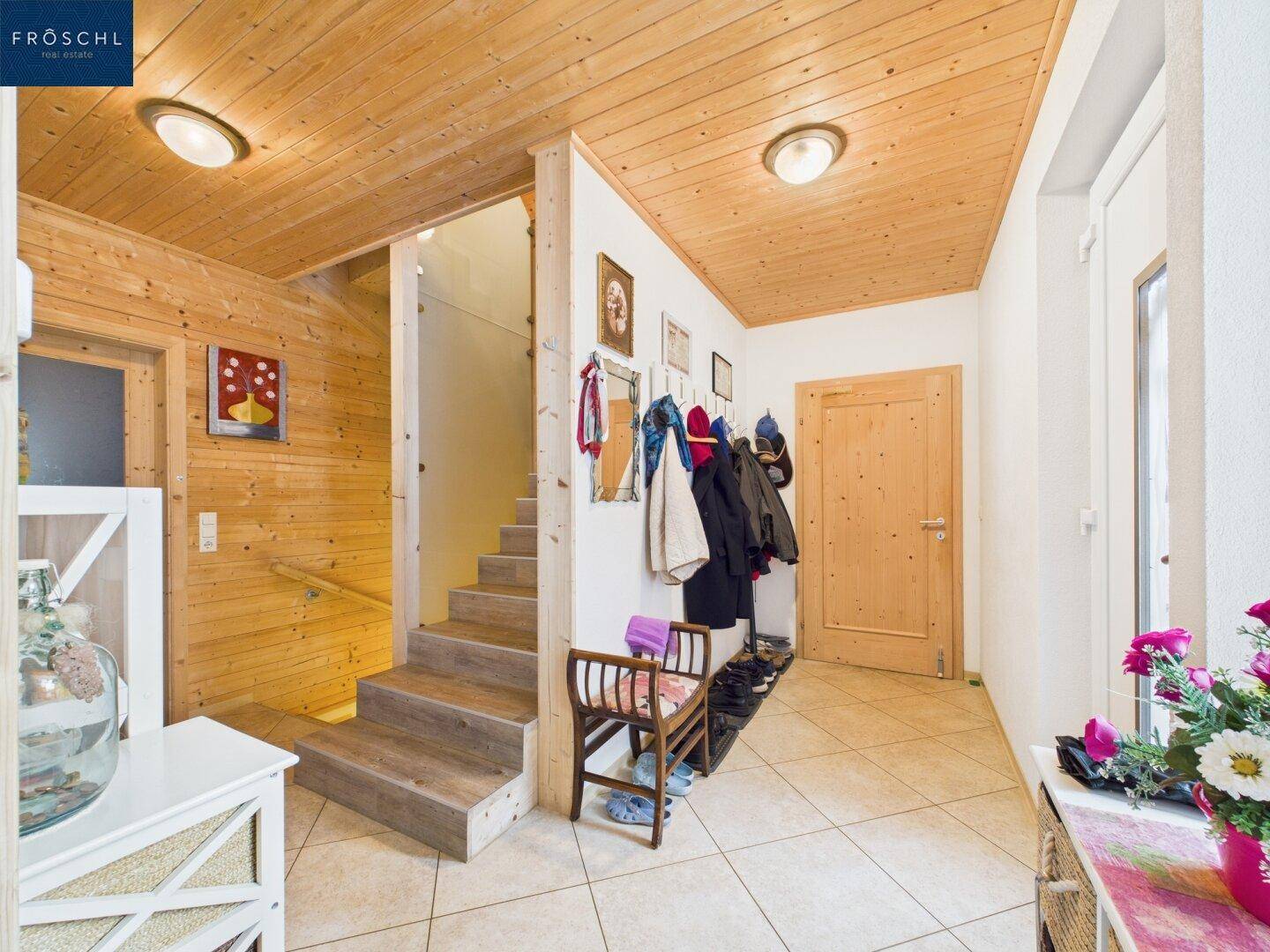 Gemütlicher Eingangsbereich mit Holzvertäfelung, gefliestem Boden und Treppe zum Obergeschoss.