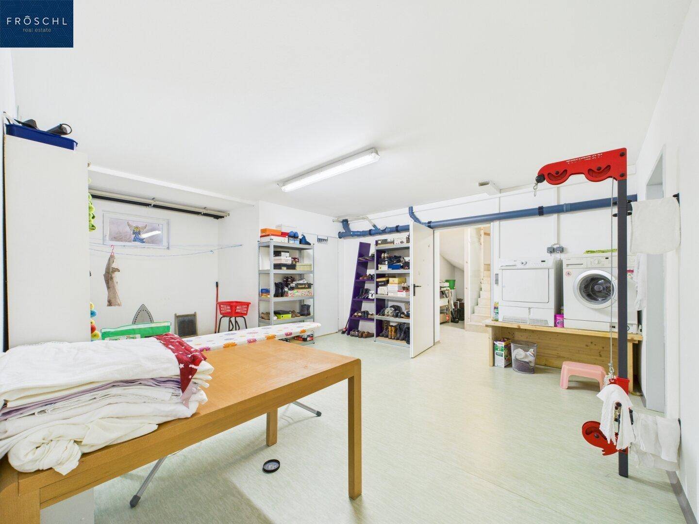 Großer Hauswirtschaftsraum mit Waschmaschine, Trockner und viel Stauraum.