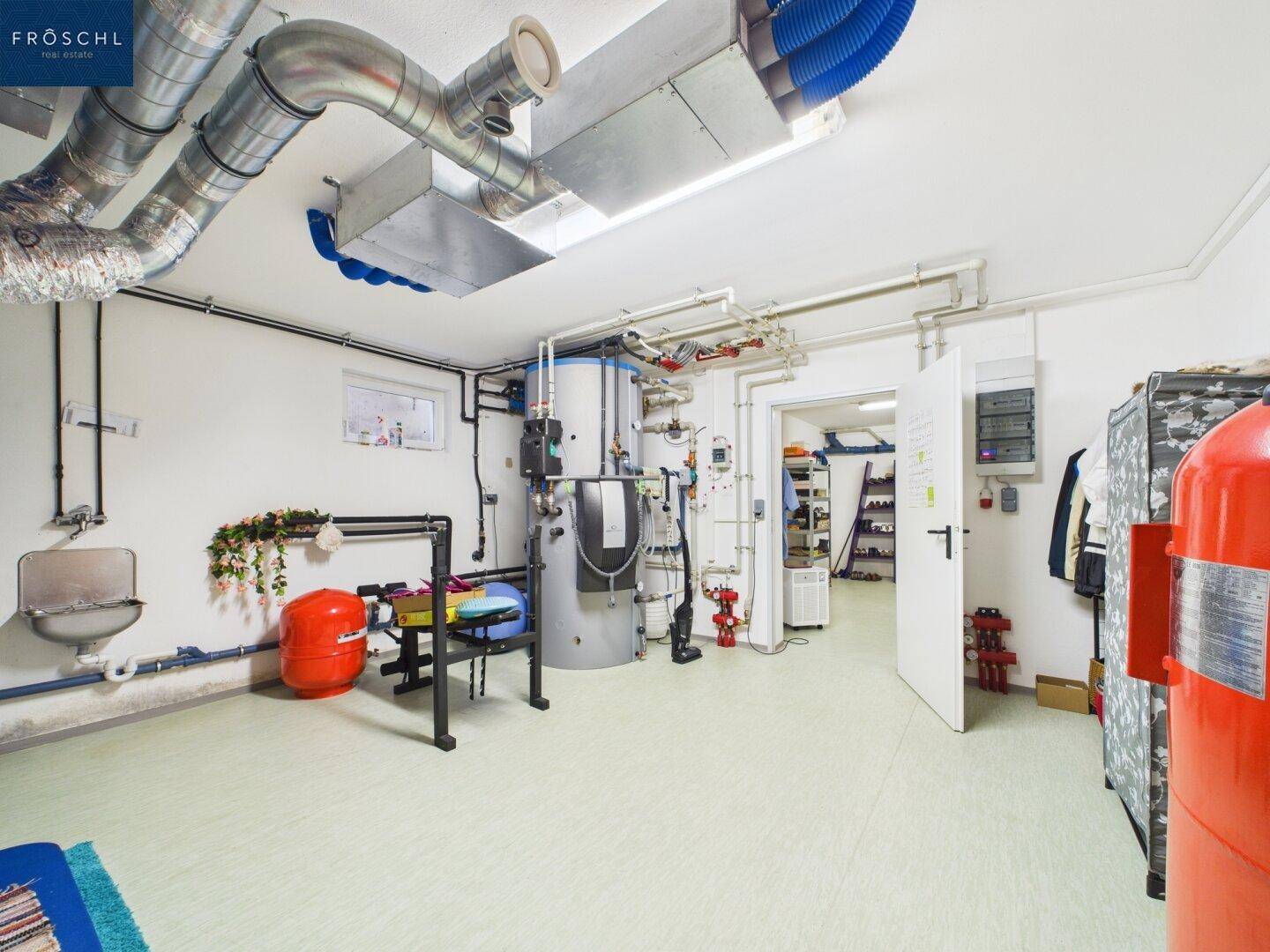 Technikraum mit Heizungsanlage, Warmwasserspeicher und sichtbaren Installationen.