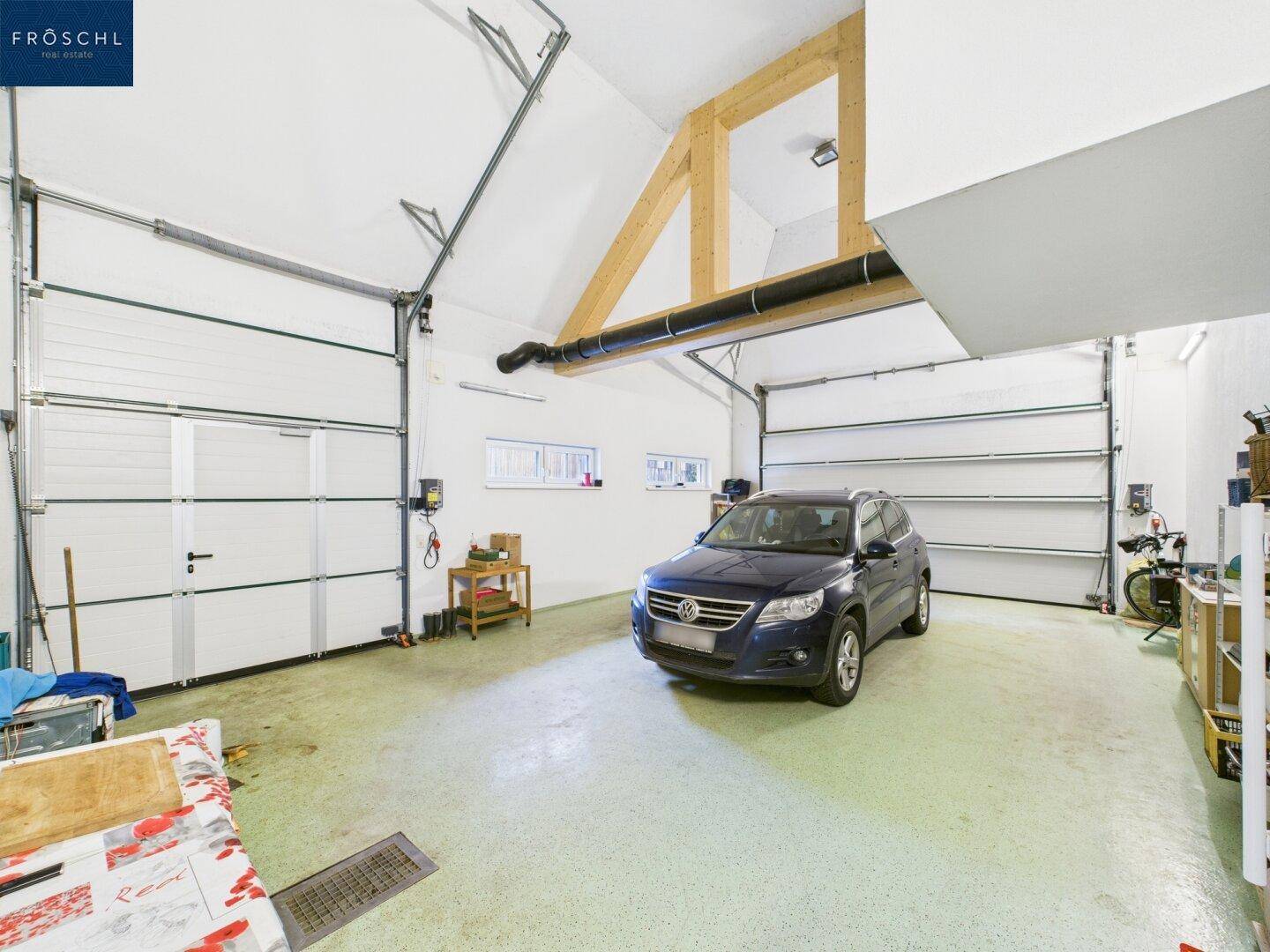 Geräumige Garage mit hohen Decken, Holzbalken und Platz für mehrere Fahrzeuge.