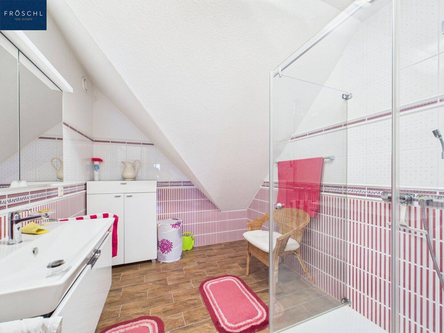 Badezimmer im Dachgeschoss mit Schrägdach, Dusche und farbigen Fliesen.