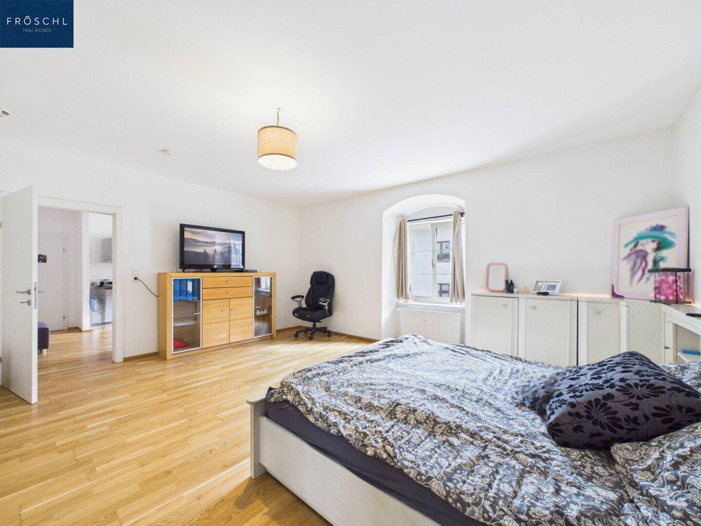 Geräumiges Schlafzimmer mit Holzboden, Doppelbett und TV-Möbeln.