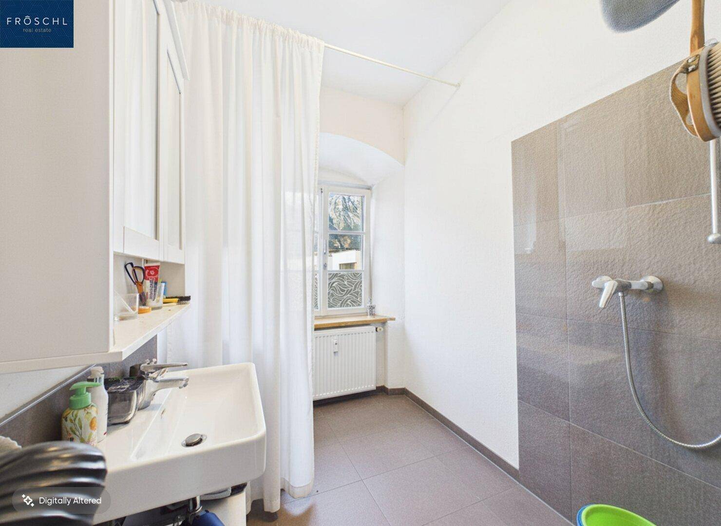 Helles Badezimmer mit Dusche, Waschbecken und Fenster.