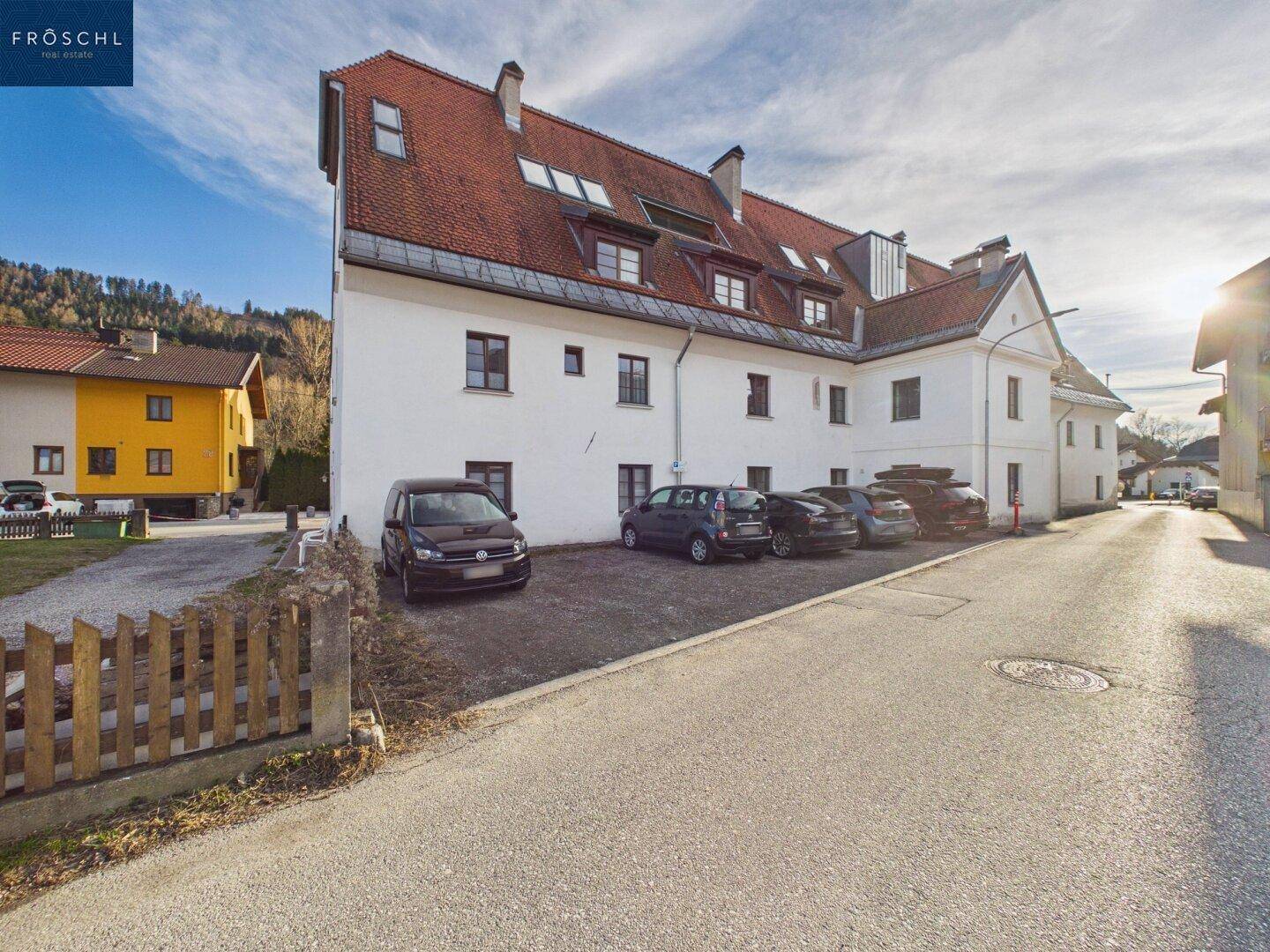 Rückansicht des Gebäudes mit Parkplätzen und Blick auf die umliegende Landschaft.